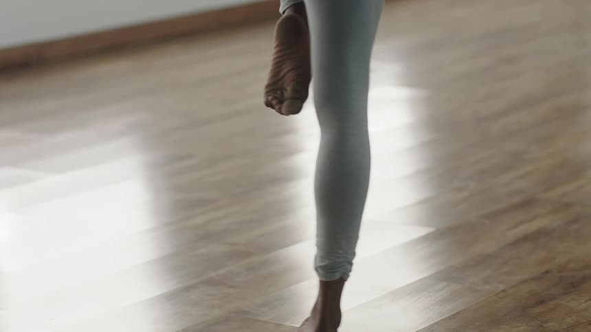 A young black woman is stretching indoors