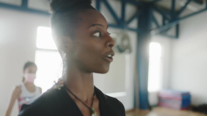 A dance instructor instructs her students in a dance studio during the day