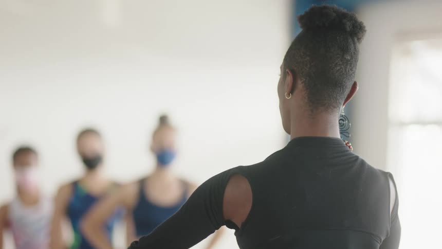 Dance instructor talks and demonstrates while giving lesson to students in dance studio