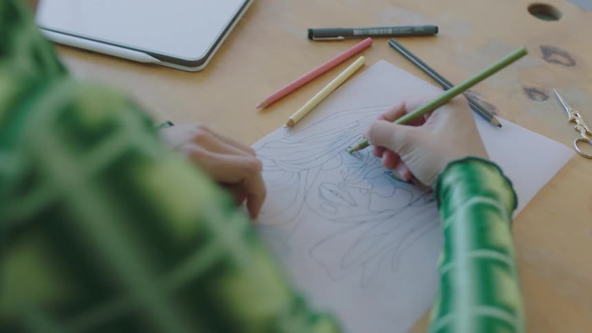 A female is sketching a picture while sitting at a table