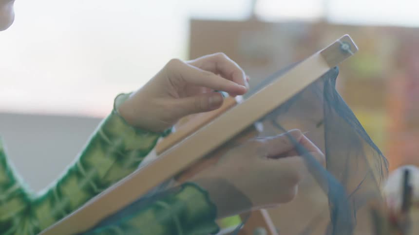 A female is sitting in a room and making crafts