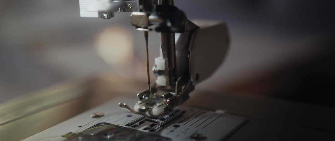 Foot on sewing machine sits in the up position over the feeder plate