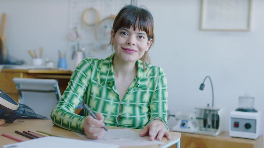 Woman in embroidery workshop sketches with colored pencils