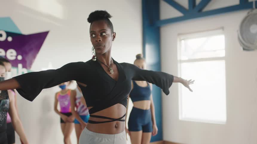 A dancer instructor teaches a group of girls in a studio during the day