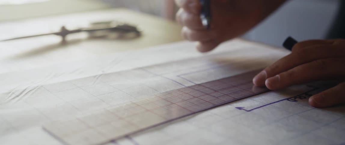 Tailor designs clothing patterns with a ruler on a sewing workshop