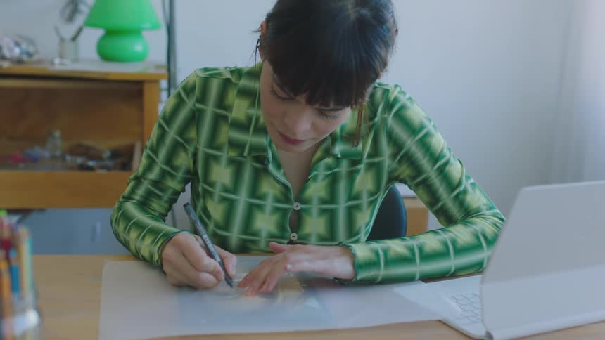 Woman copies a drawing by hand using translucent paper and a marker