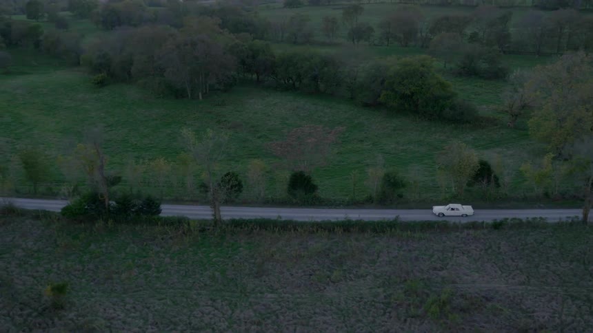 A white vehicle travels down the road below