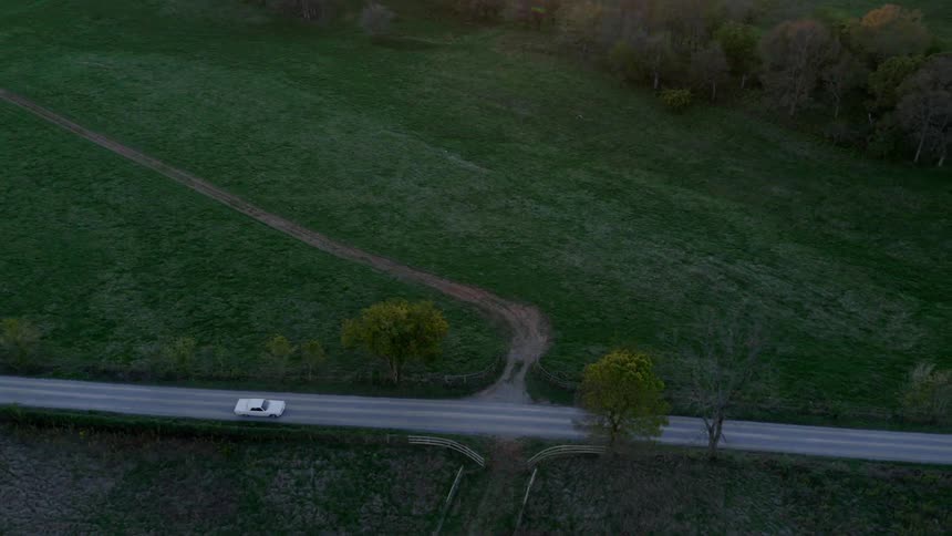 A white car drives on the road