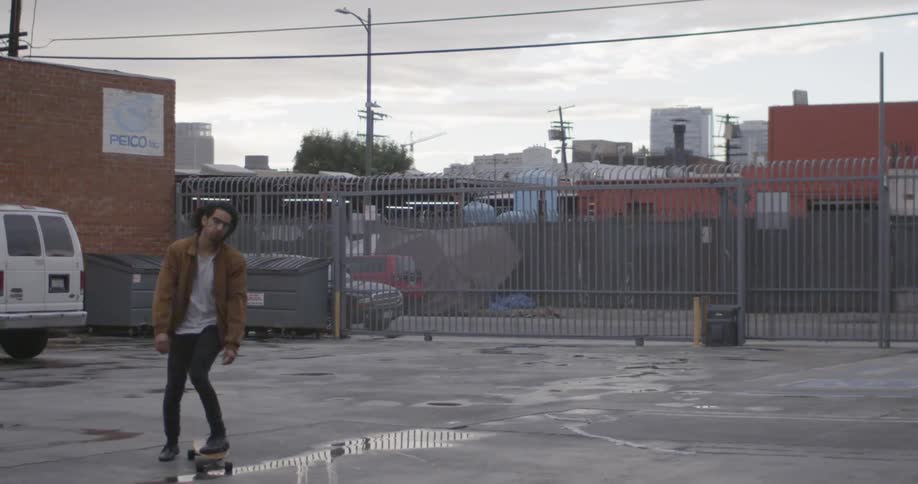 A man is skateboarding in a lot on a cloudy day