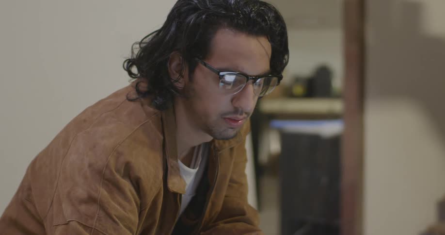 A man wearing glasses is leaning forward