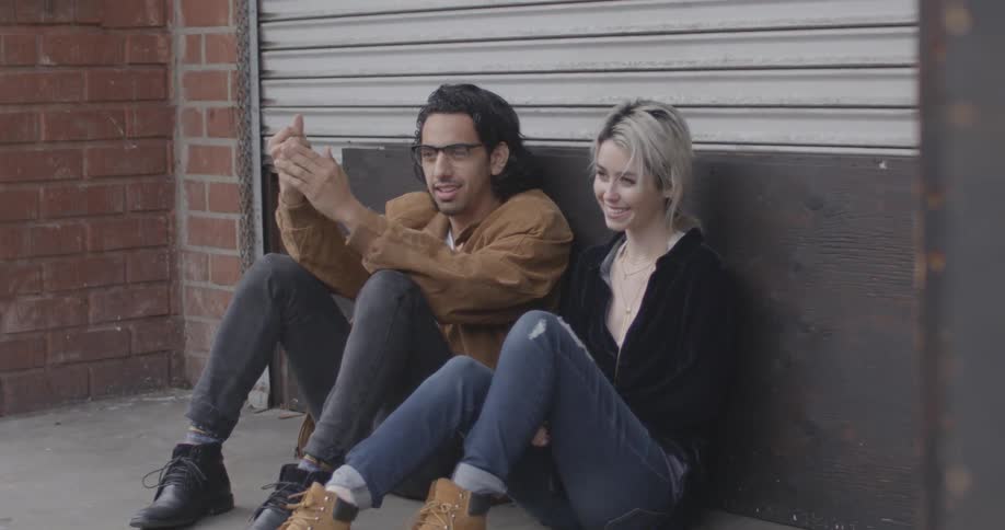 A man and woman sit near a gate and talk