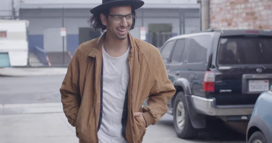 A man walks down an alley while talking and smiling