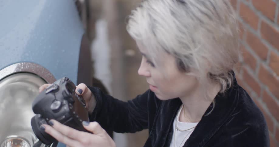 A female photographer snaps a picture then looks at the results and says something