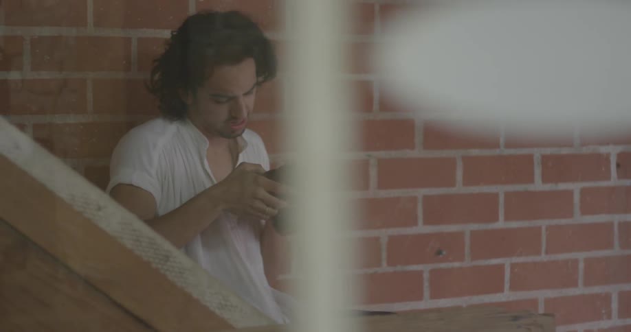 A photography sits near a wall and takes a picture