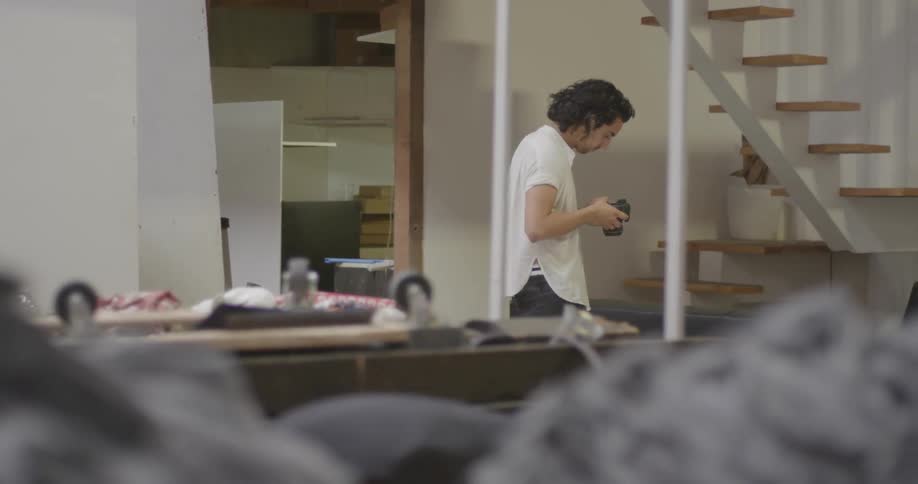 A man is walking around inside looking at a camera