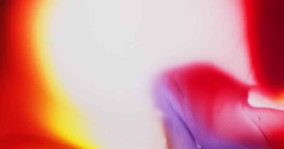 Waves of colorful bright liquid ink flowing out over a white background