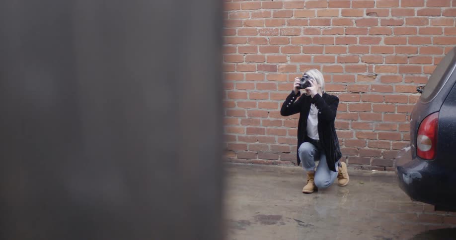 A woman kneels and takes a photo before moving over