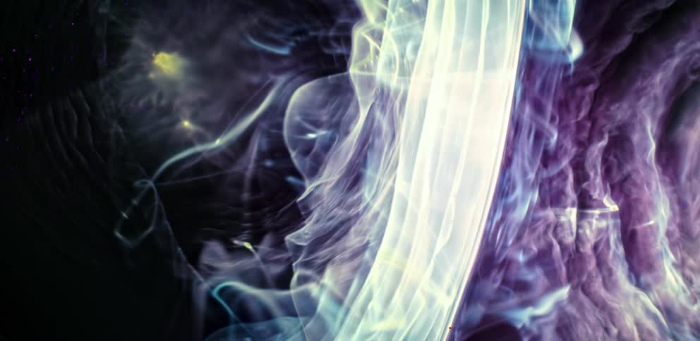Strands and wisps of purple and blue colors floating against a black background