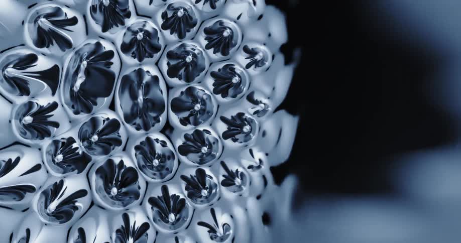 Liquid silvery bubbles form and flow across dark