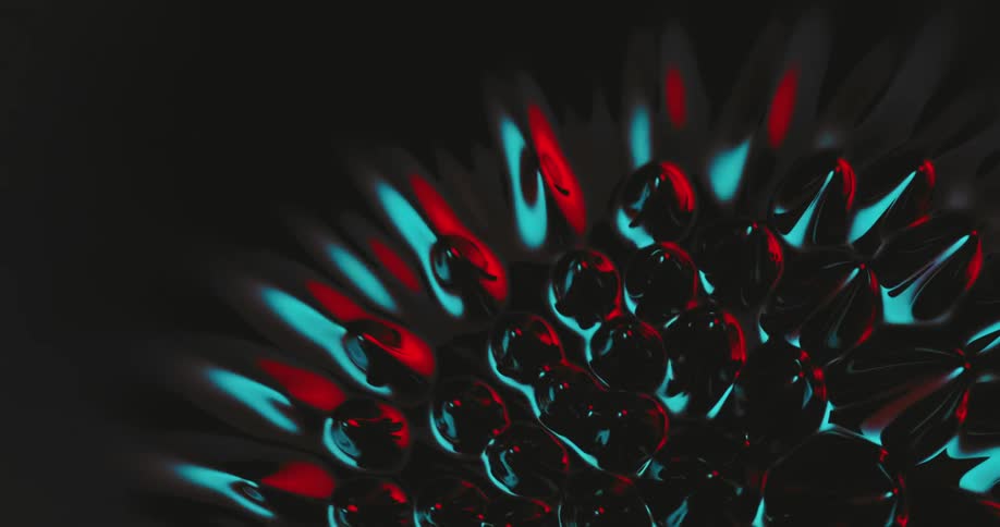 Top down view of spikes growing out of a black liquid reflecting red and blue lights