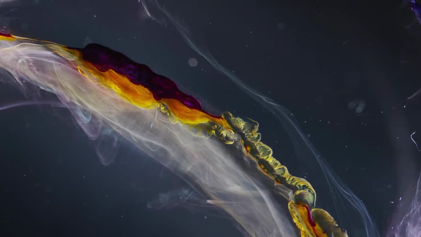 Waves of yellow and white liquid ink flowing up over a dark background
