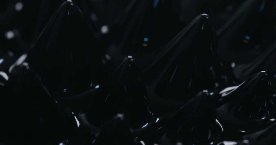 Black peaks form in thick liquid reflecting light and shimmering