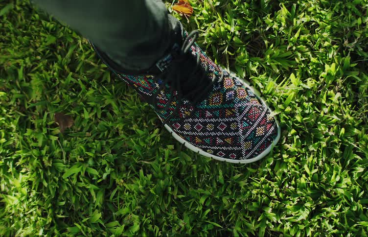 A person is tying their shoe in a grassy area