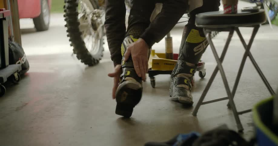 Men are sitting in a garage and putting on shoes