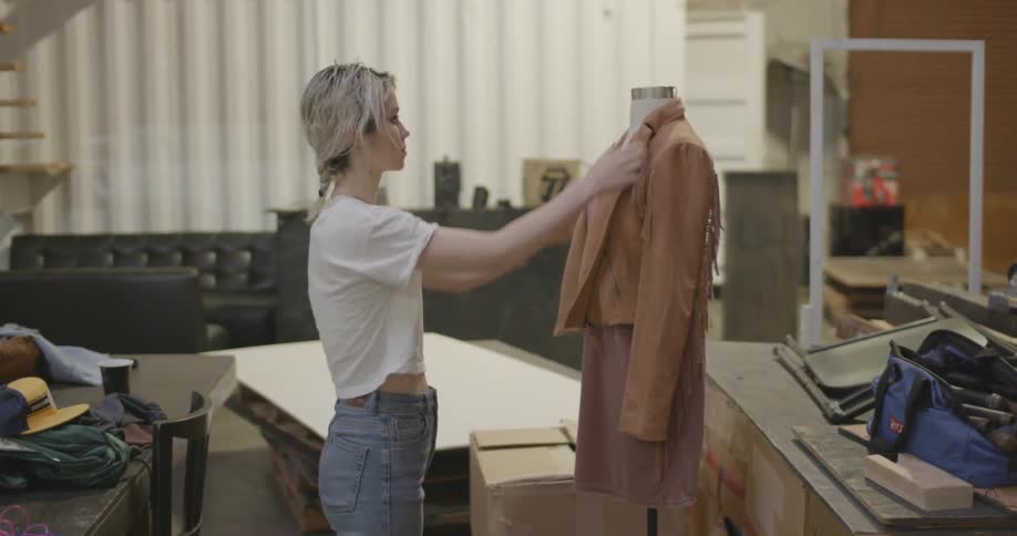 A woman unzips and looks at a jacket on a dress form