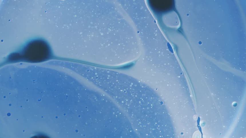 Translucent bubbles flow and spread against blue background with small particles