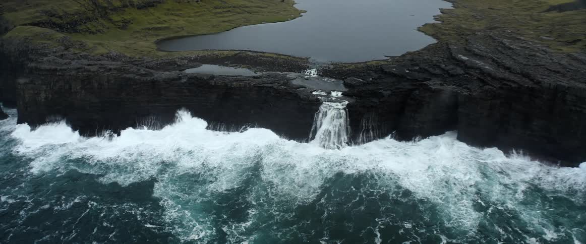 An aerial view of a waterfall crashing in to the ocean