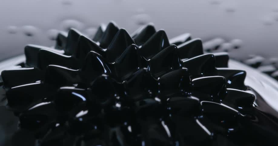 Ring of spikes rise and move over a dark reflective liquid