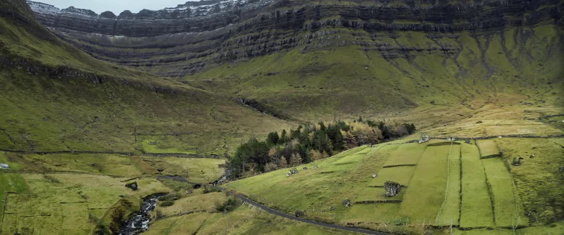 An aerial view of a grassy field and trees surrounded by cliffs