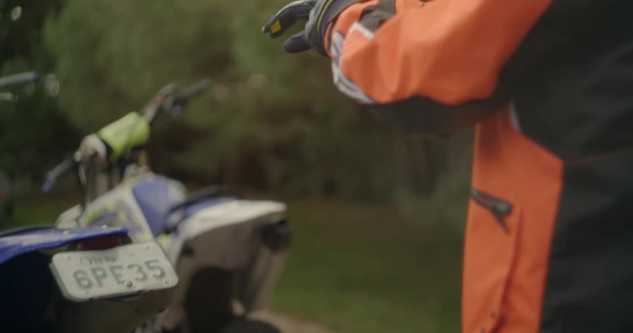 A rider standing behind his bike putting his gloves on