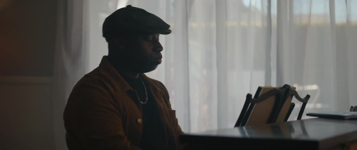 Silhouette of a man playing the piano inside a dimly lit room during the day