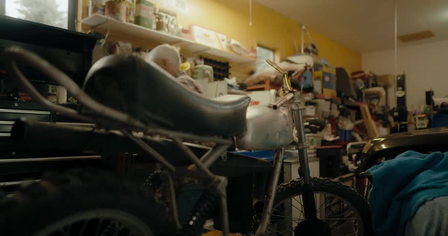 Elderly man searching for tools on his garage to repair a vintage motorcycle