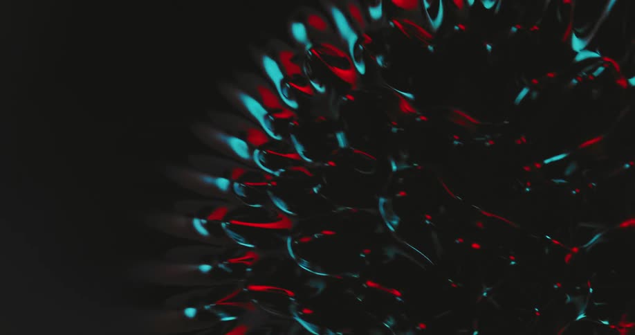Top down view of spikes growing out of a black liquid reflecting red and blue lights