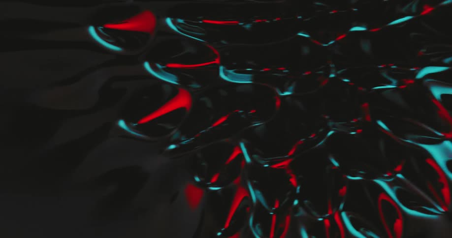 Mass with red black and blue nodules flows across oily liquid
