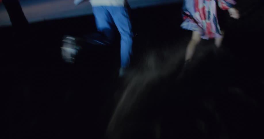 A man and woman are running through the dark