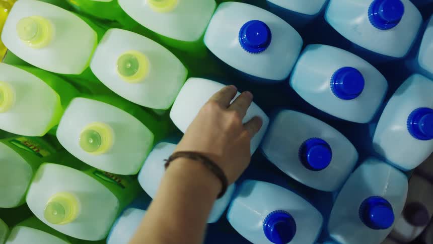 Overhead view of person picking up detergent bottle from display