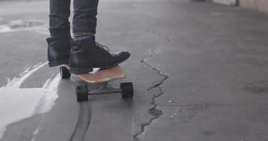 A person skateboards past a puddle