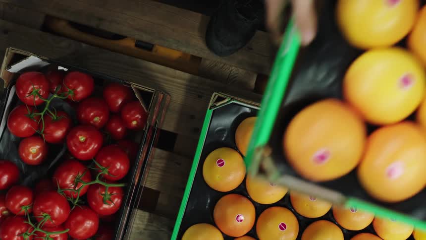 A person loading crates of produce onto a wooden palette