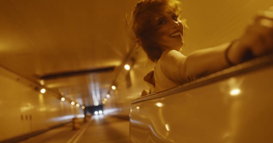 Young woman sitting on the back of a truck driving through a tunnel