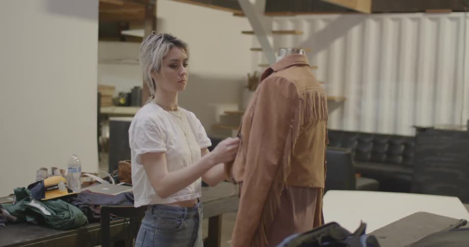 A woman is checking out a jacket on a mannequin