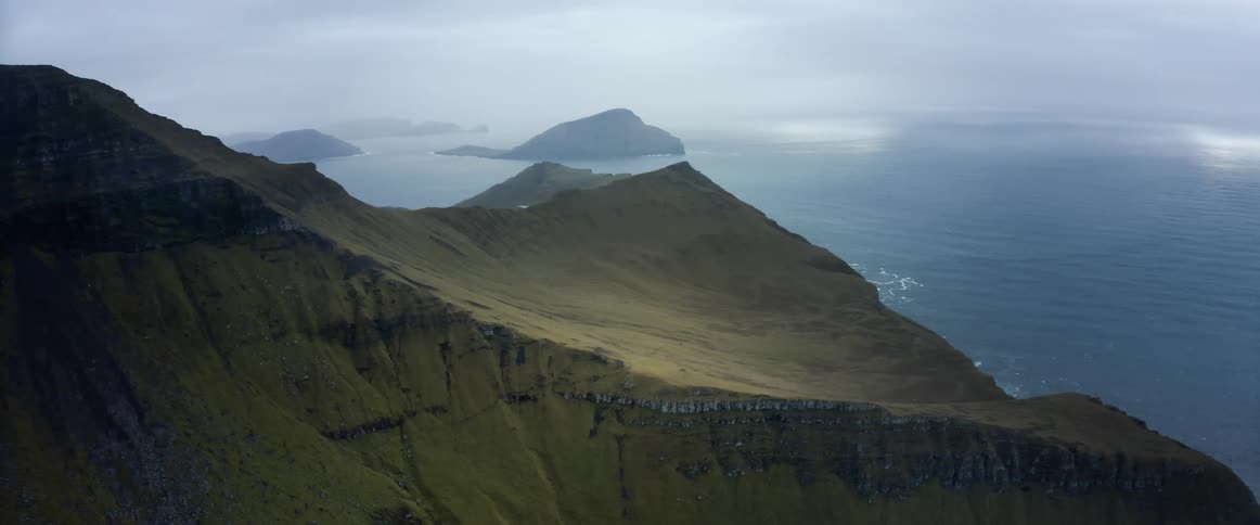 The view is of the ocean and mountain in the middle of the day