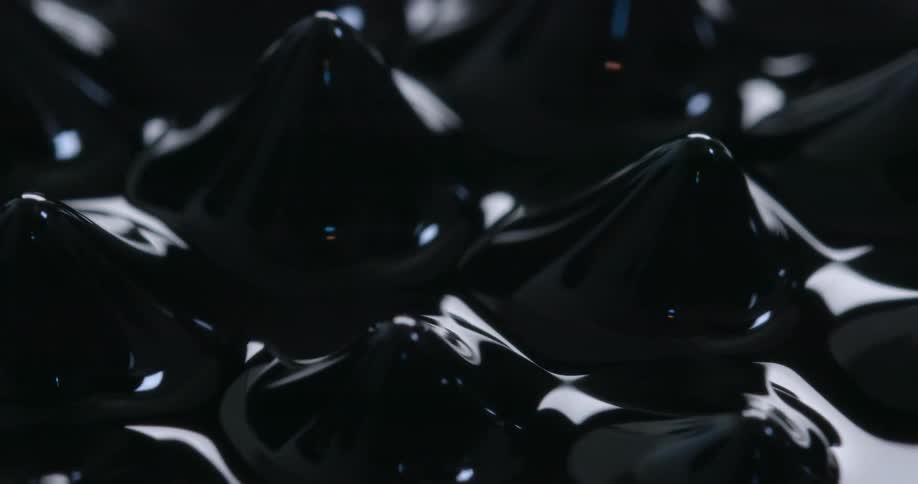 Close up of spikes protruding from the surface of a bright black liquid