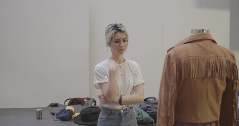 A woman puts a jacket on a form and steps back to assess it