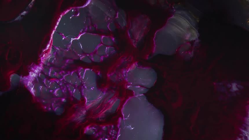 Red purple mass spreads an moves against grayish background