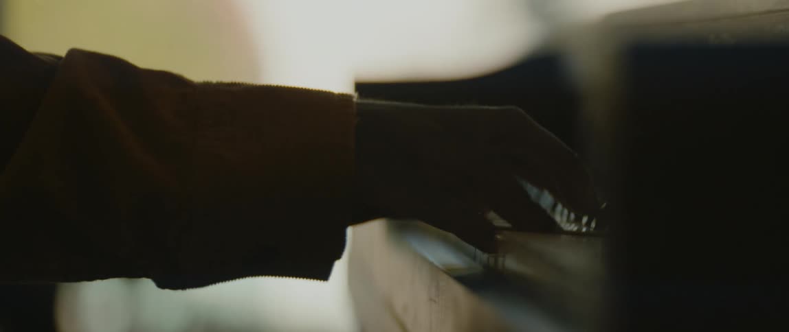 A young black man is playing the piano inside his room