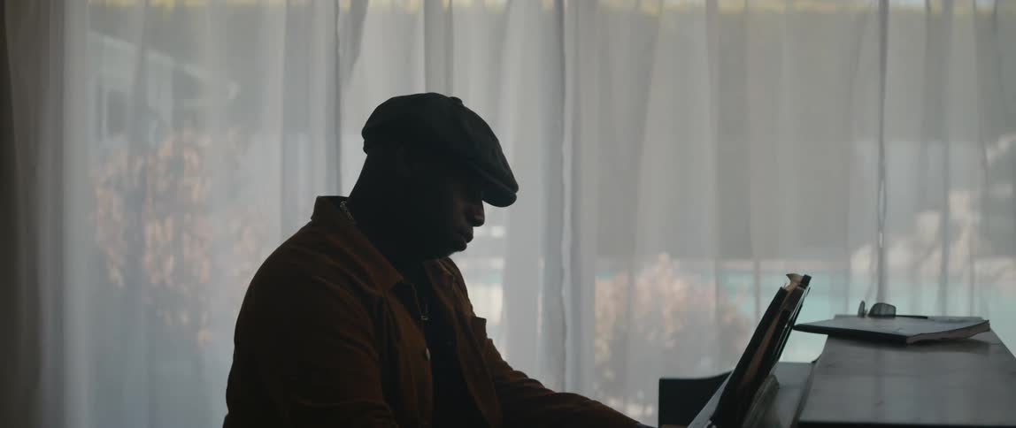 A young black man is playing the piano inside his home